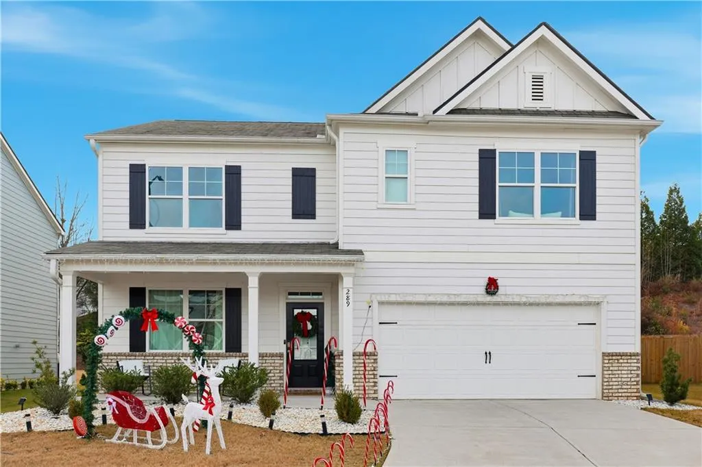 View of front of home featuring a porch, board and batten siding, an attached garage, driveway, and brick siding