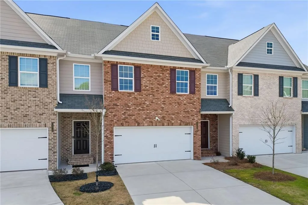 View of front of house with driveway, a shingled roof, an attached garage, and brick siding