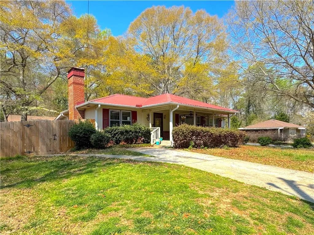 View of front of home featuring a porch, a chimney, and a metal roof