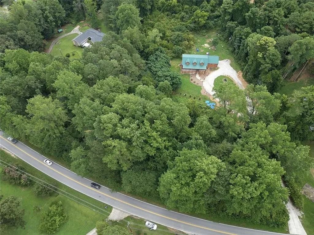 Aerial view of property and surrounding area with a forest