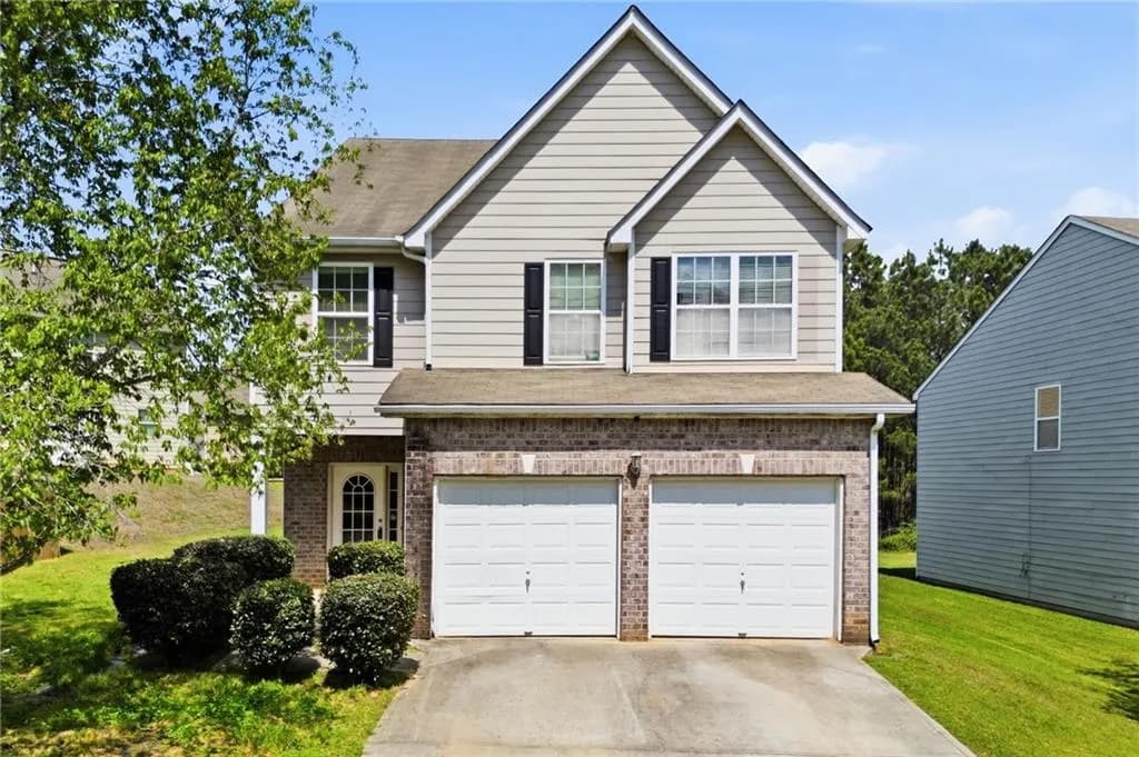 View of front of property with an attached garage, brick siding, concrete driveway, and a front yard