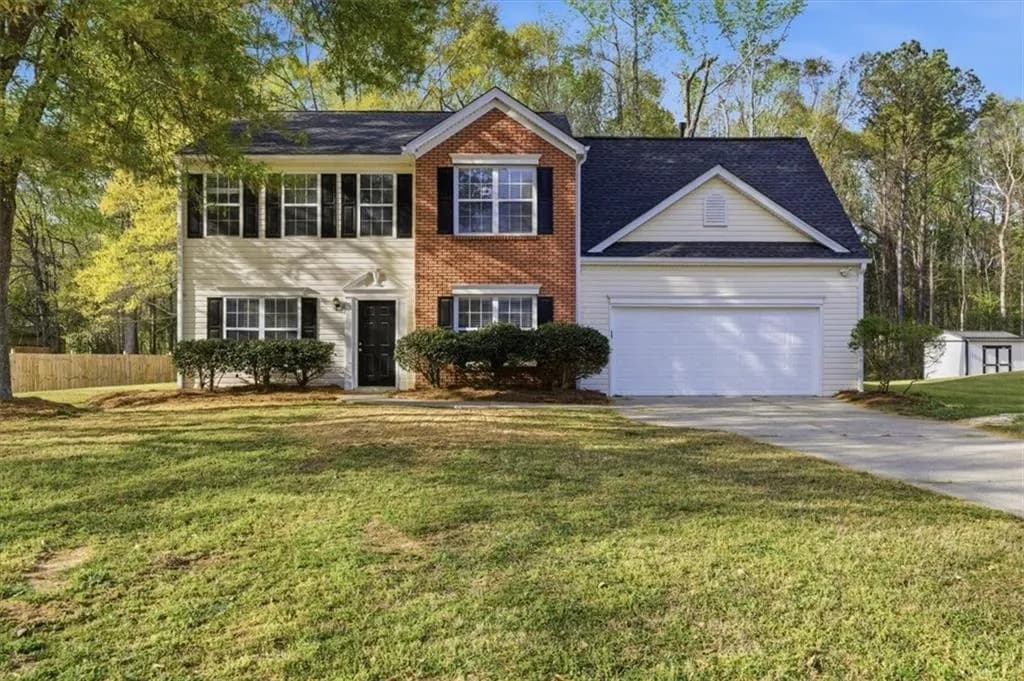 Colonial-style house featuring a front yard, concrete driveway, and an attached garage