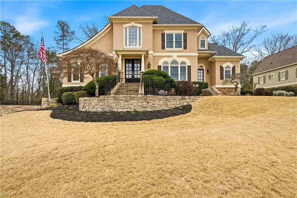 View of front of home with stucco siding, a front lawn, and french doors