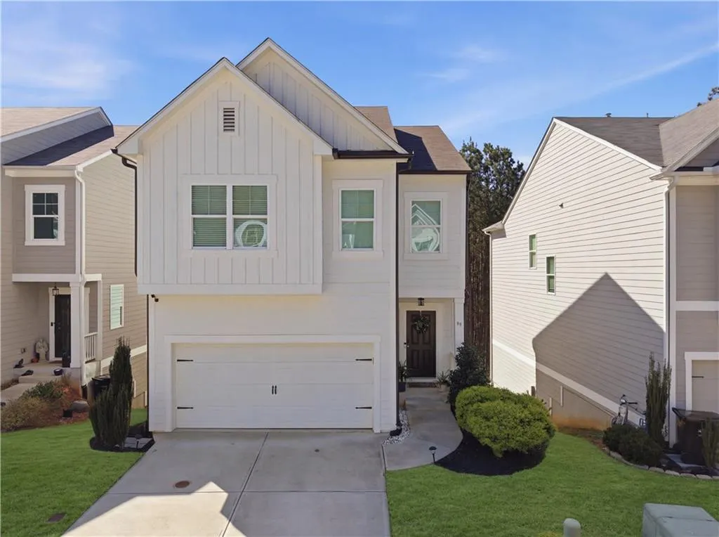 View of front of house featuring board and batten siding, an attached garage, concrete driveway, and a front lawn
