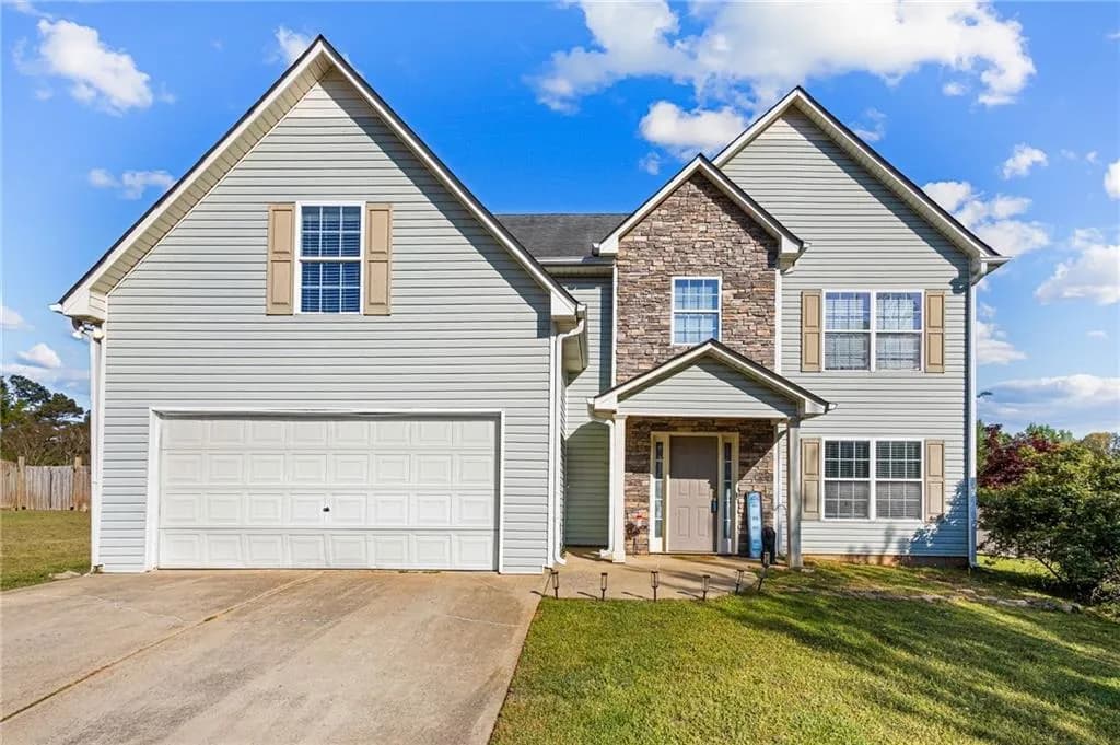 Traditional-style house featuring stone siding, driveway, and an attached garage