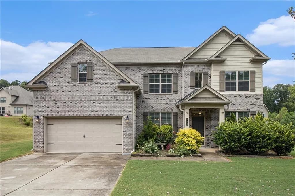 View of front of home with brick siding, a front lawn, a garage, and concrete driveway