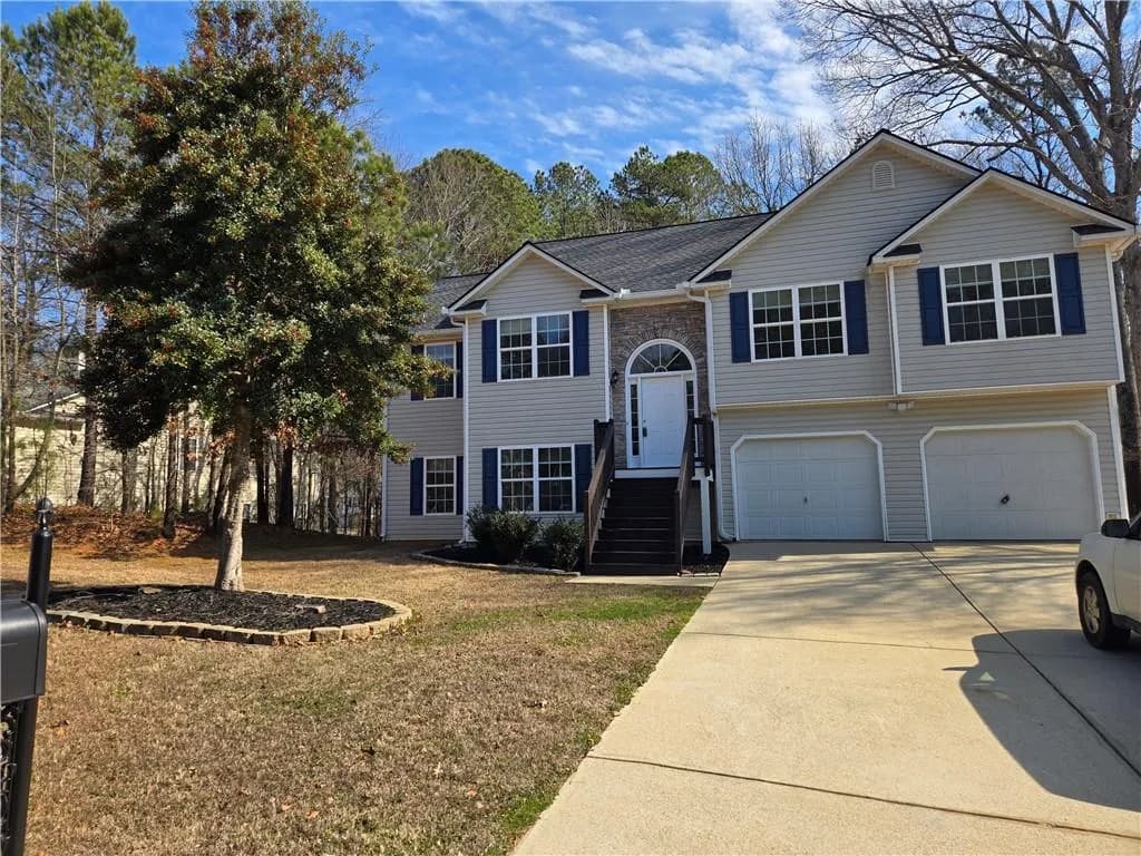 Split foyer home featuring a garage, concrete driveway, a front yard, and a shingled roof