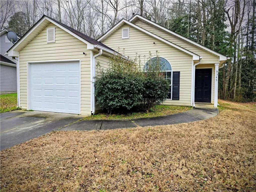 Ranch-style house featuring driveway, a front yard, and an attached garage