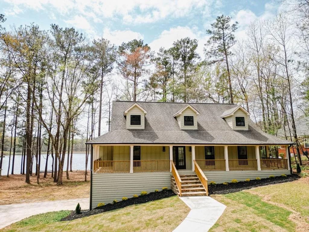 View of front of home with board and batten siding, covered porch, roof with shingles, and a front yard