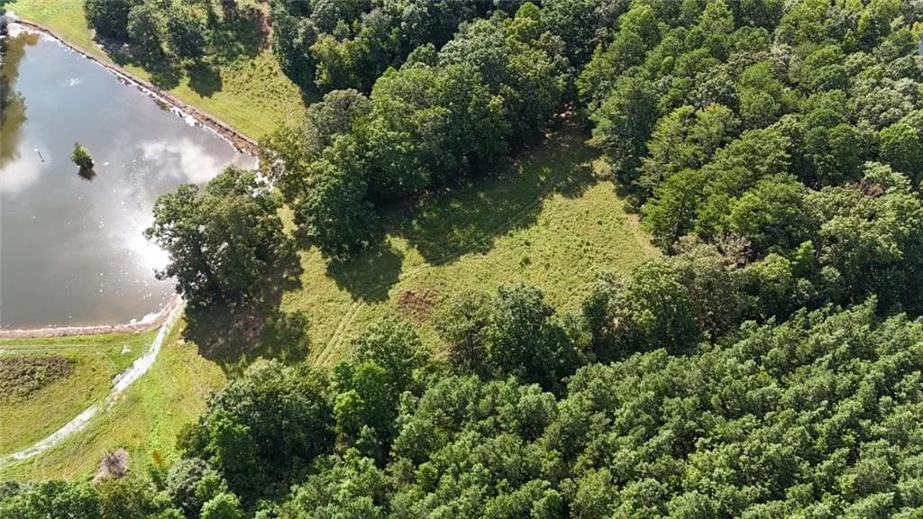 Aerial overview of property's location featuring a large body of water and a heavily wooded area