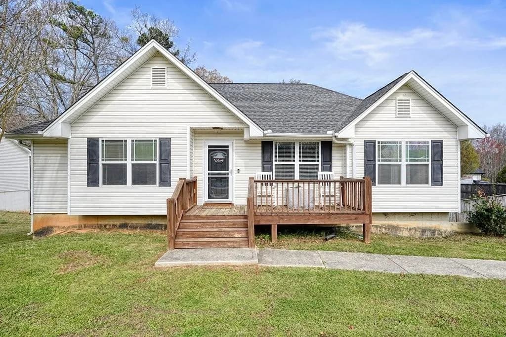 Bungalow featuring a front yard, roof with shingles, and a deck
