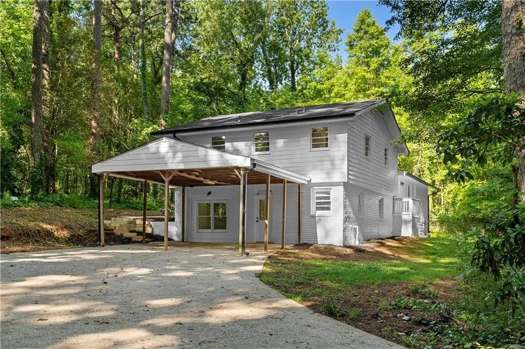 The property features a light-colored exterior with a dark roof and a covered carport