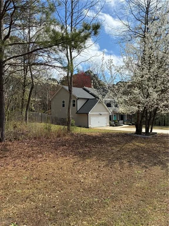 View property featuring an attached garage, board and batten siding, driveway, and roof with shingles