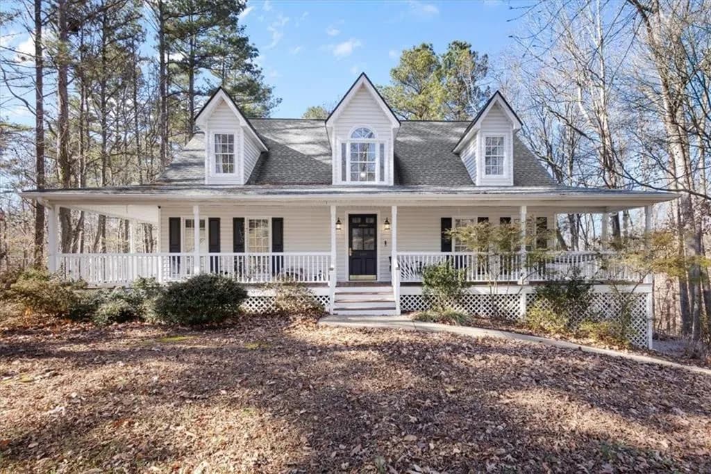 The property features a charming exterior with dormer windows, a full-length front porch with white railings, and dark shutters
