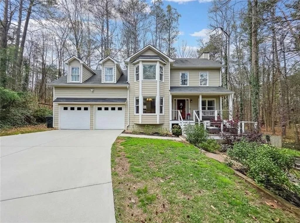 View of front of house with covered porch, a front yard, concrete driveway, and a chimney