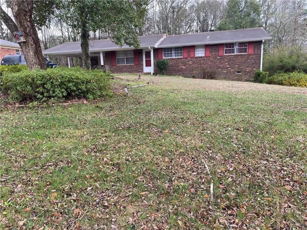 Single story home with brick siding, crawl space, a front yard, and an attached carport