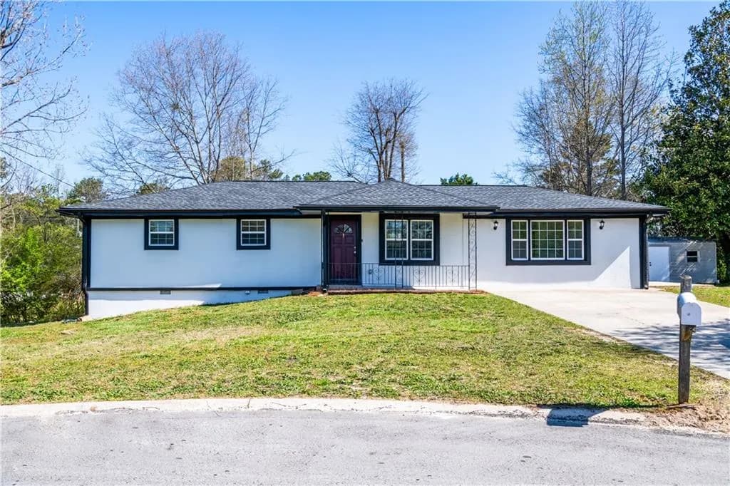Single story home featuring a front yard, roof with shingles, stucco siding, and driveway