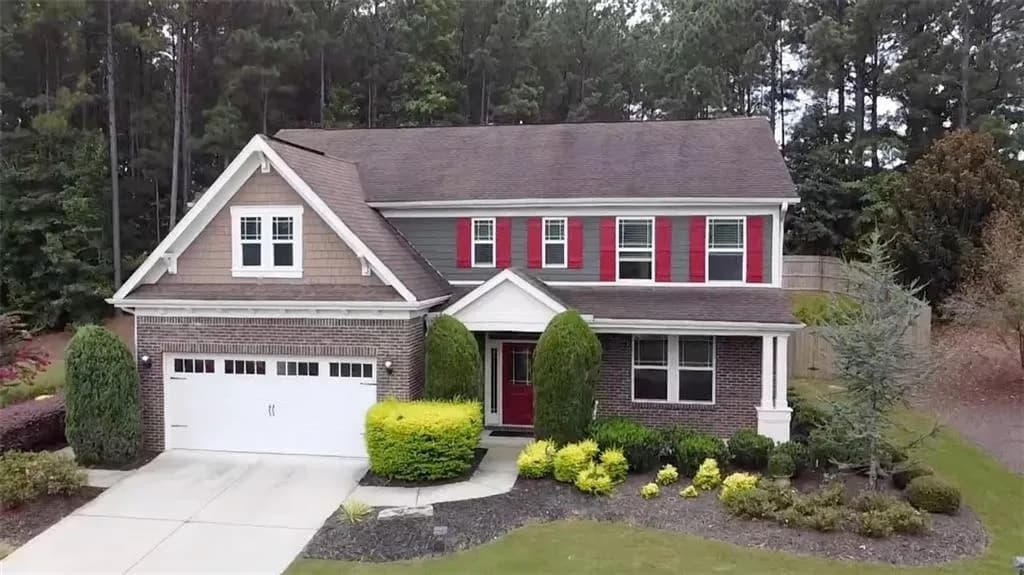 View of front facade featuring brick siding, concrete driveway, and roof with shingles