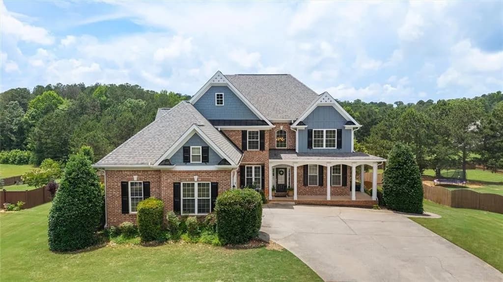 Brick and siding exterior featuring a covered front porch with white columns, a multi-gabled roofline, and a concrete driveway