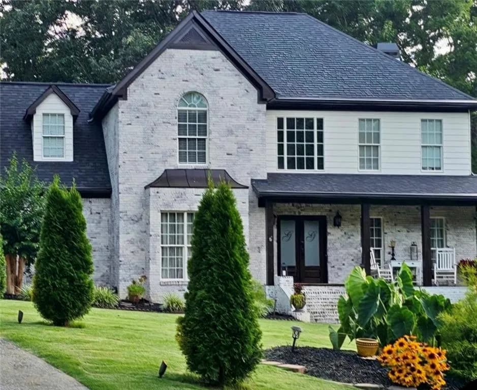 Brick and siding exterior featuring dark trim and a prominent front porch