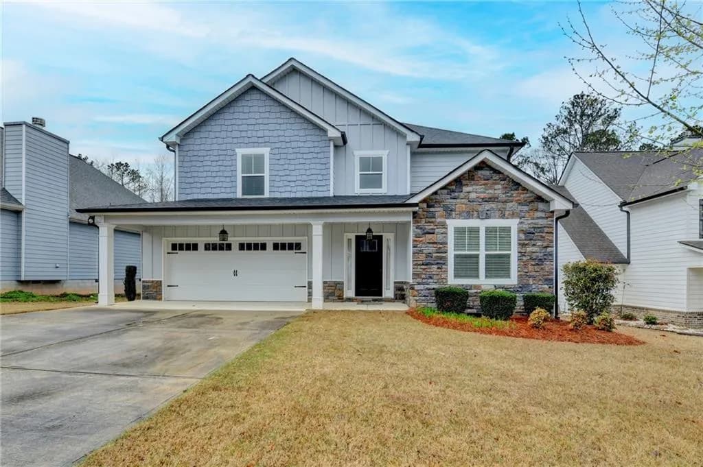 Craftsman-style home with board and batten siding, a porch, an attached garage, driveway, and a front lawn