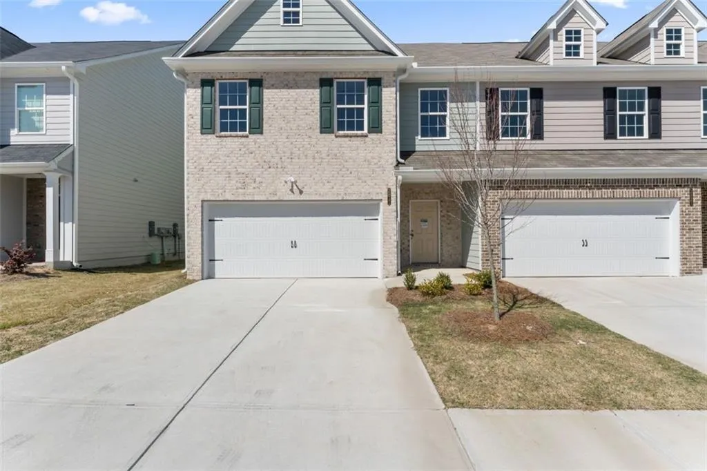View of property featuring driveway, brick siding, and a garage