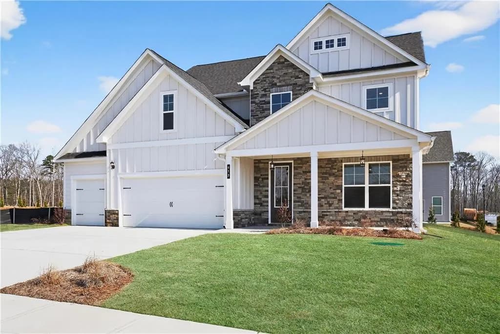 View of front of property featuring board and batten siding, stone siding, a front yard, a porch, and driveway