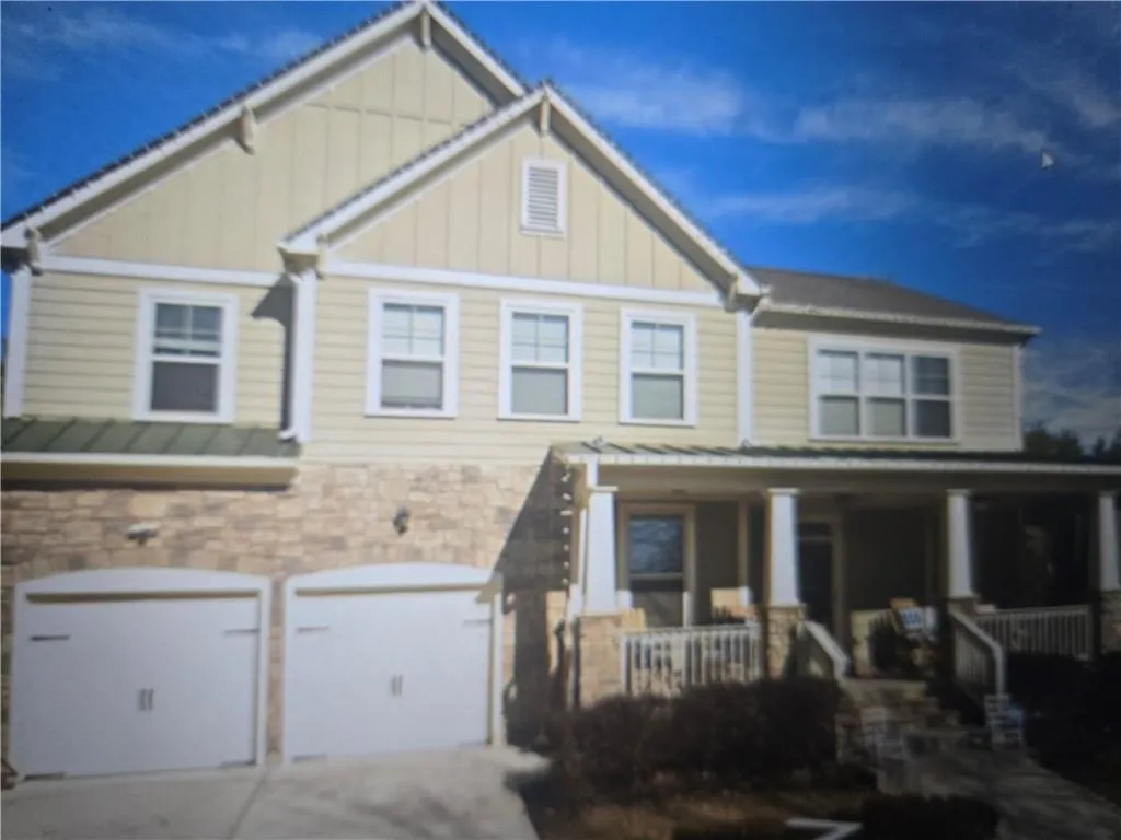 Craftsman-style home featuring stone siding, board and batten siding, covered porch, driveway, and an attached garage