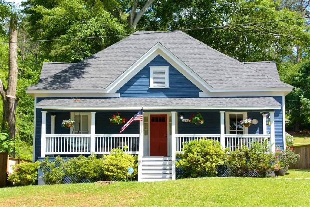 View of front facade with covered porch and a shingled roof