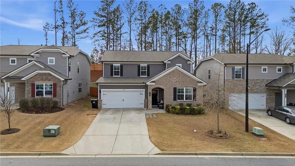 Traditional-style home with concrete driveway, roof with shingles, a garage, brick siding, and a front lawn