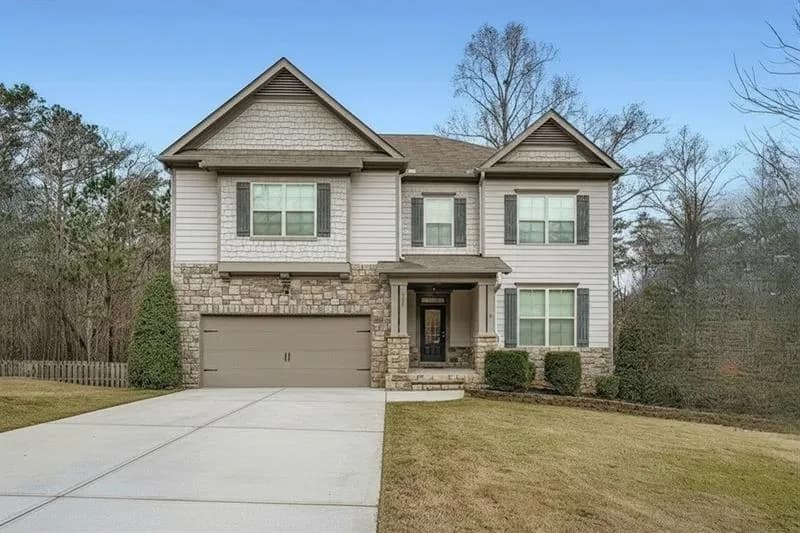 Craftsman-style house featuring stone siding, a front yard, a garage, and driveway