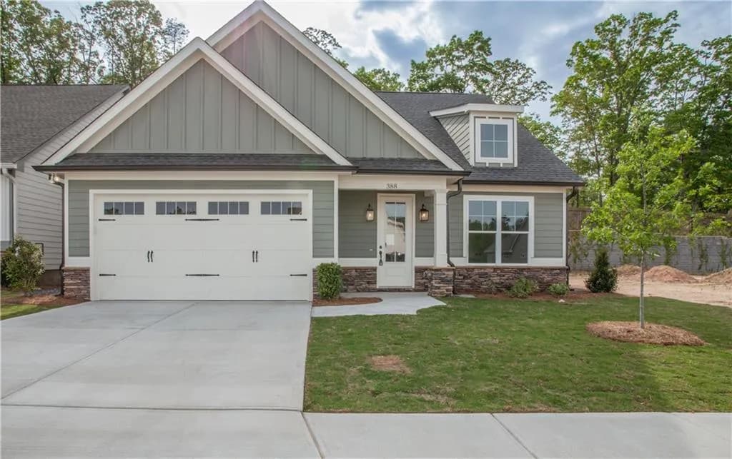 Craftsman-style home with stone siding, roof with shingles, a porch, driveway, and a garage