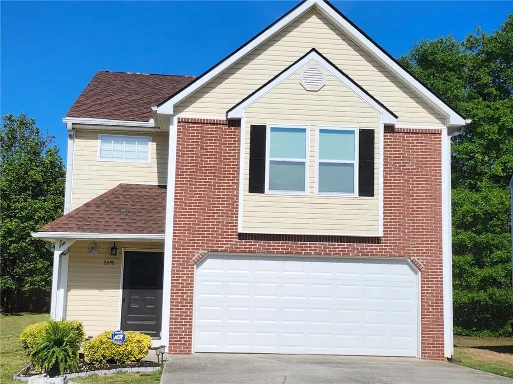 Traditional-style home with roof with shingles, driveway, an attached garage, and brick siding