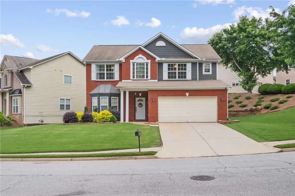 View of front facade featuring brick siding, a garage, driveway, and a front lawn