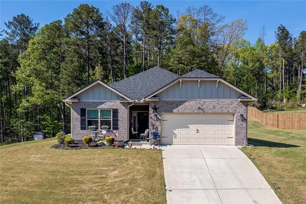The property features a brick exterior with a gray shingled roof, an attached garage, and a concrete driveway