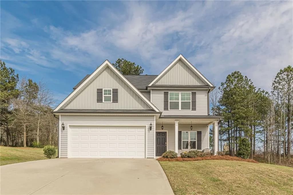 View of front facade featuring board and batten siding, a front lawn, driveway, covered porch, and a garage