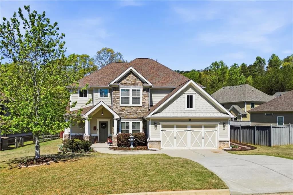 Craftsman-style house with stone siding, driveway, and roof with shingles