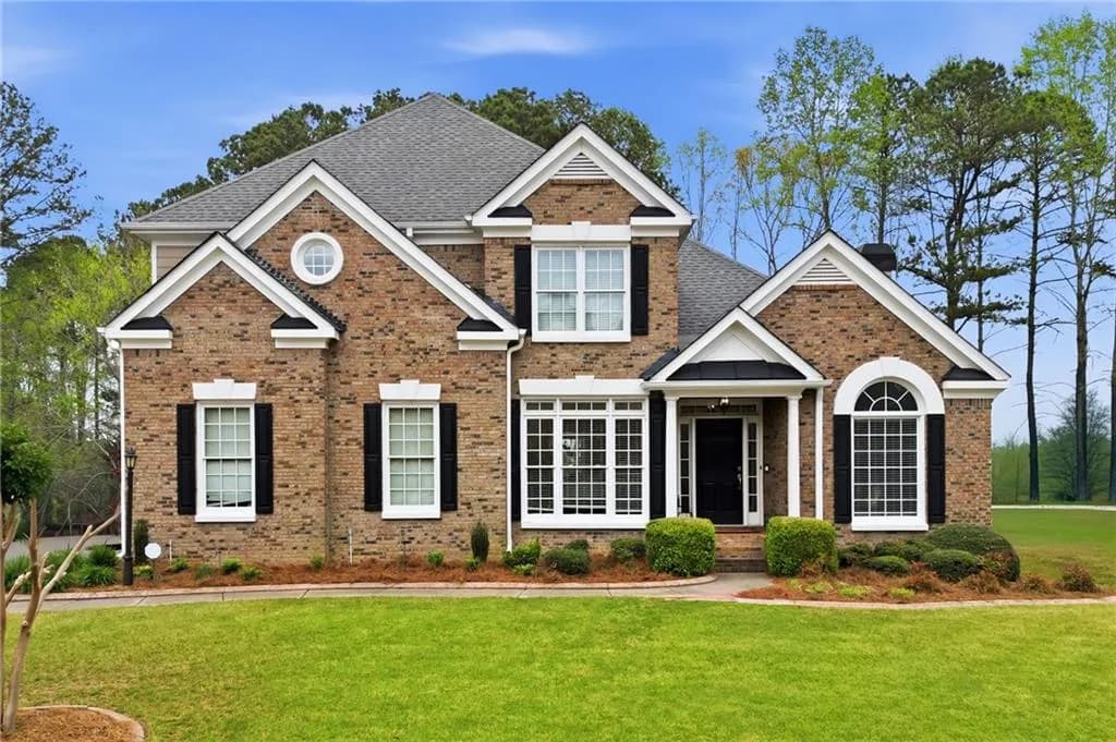 Traditional-style house with brick siding, a front lawn, and roof with shingles