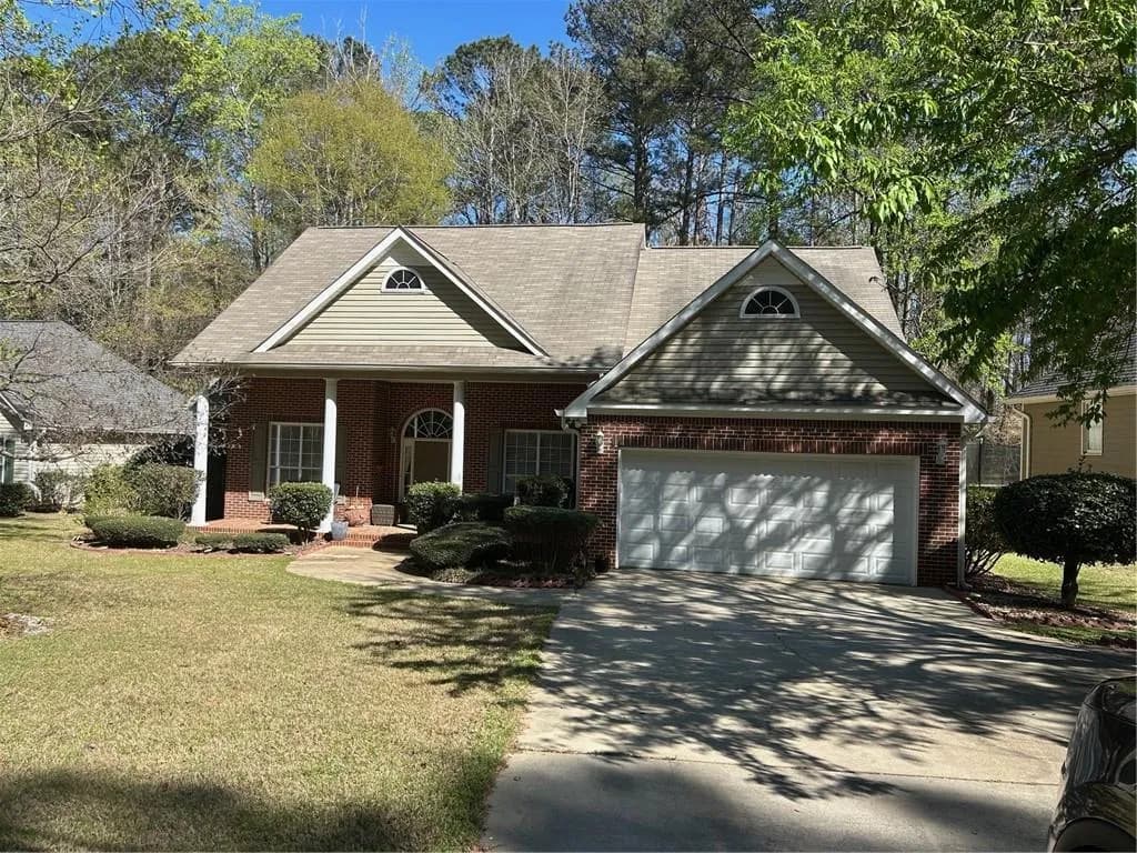 View of front facade with a front yard, covered porch, driveway, a garage, and brick siding