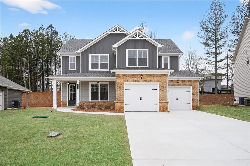 View of front of home featuring covered porch, driveway, an attached garage, and a front lawn