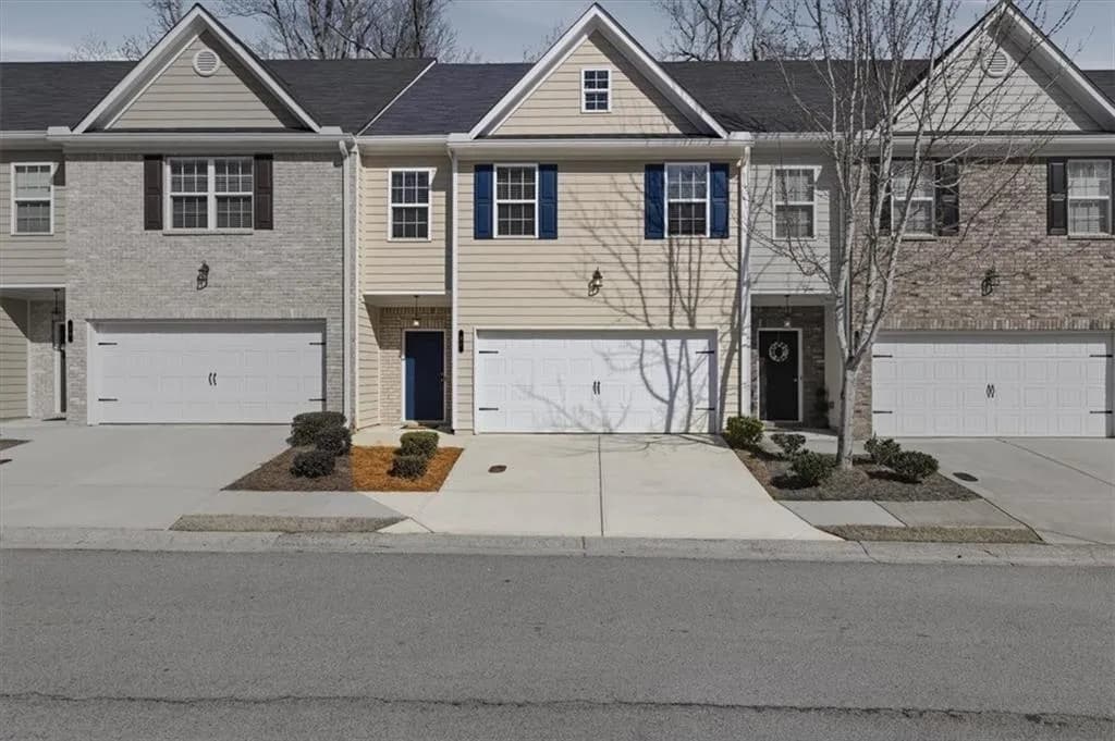 Traditional-style home with an attached garage, driveway, a shingled roof, and brick siding