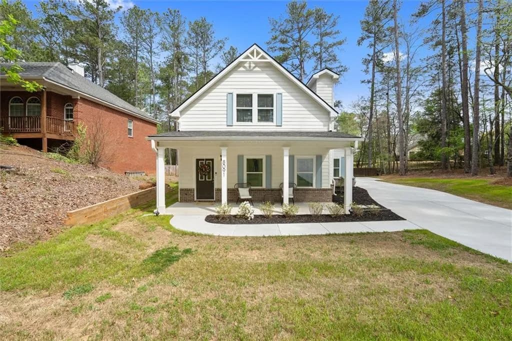 View of front of home with a porch, brick siding, a front yard, and driveway