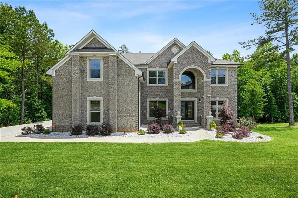 Stately brick exterior featuring a prominent arched entryway, multiple gables, and a double-door entrance