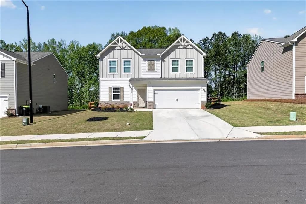 Craftsman inspired home with stone siding, board and batten siding, a garage, and a front lawn