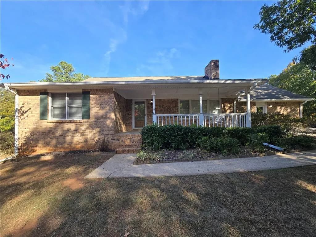 View of front of home with a porch, brick siding, and a chimney