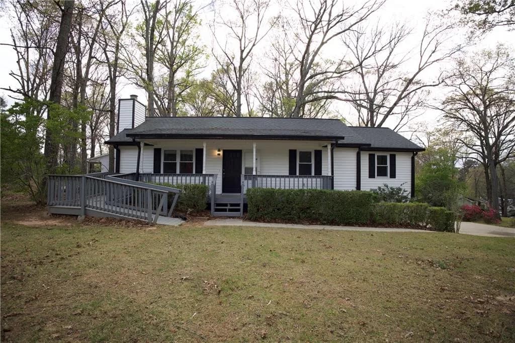Single story home featuring covered porch, a chimney, and a front yard