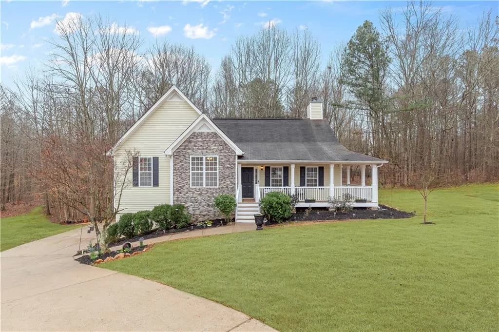 View of front of house with covered porch, a front lawn, stone siding, and a chimney