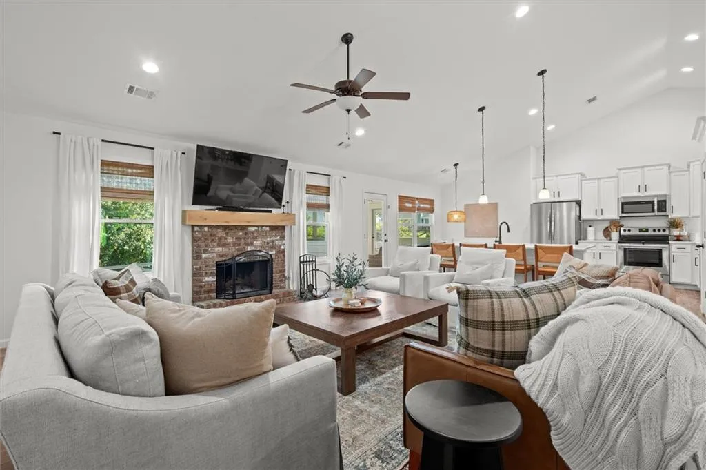 Living area with high vaulted ceiling, a brick fireplace, recessed lighting, a ceiling fan, and light wood-type flooring