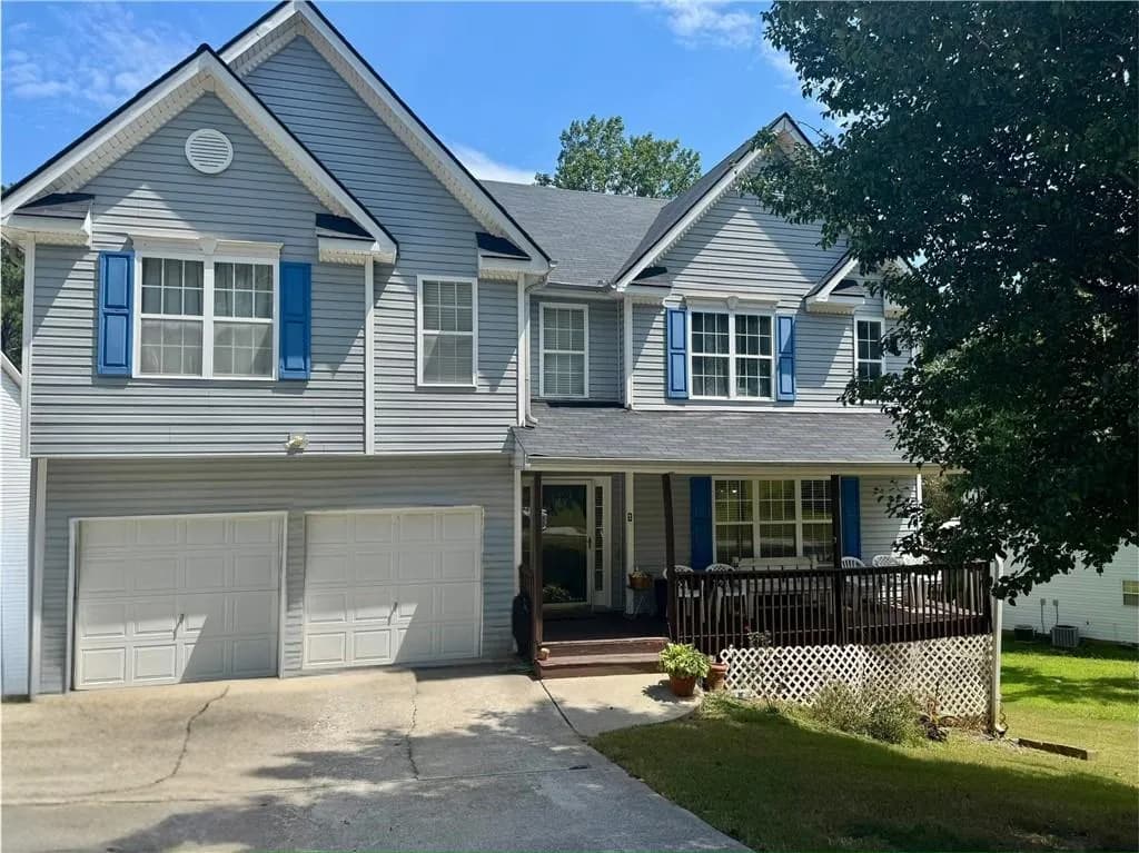 View of front of home with a porch, concrete driveway, a front lawn, and a garage