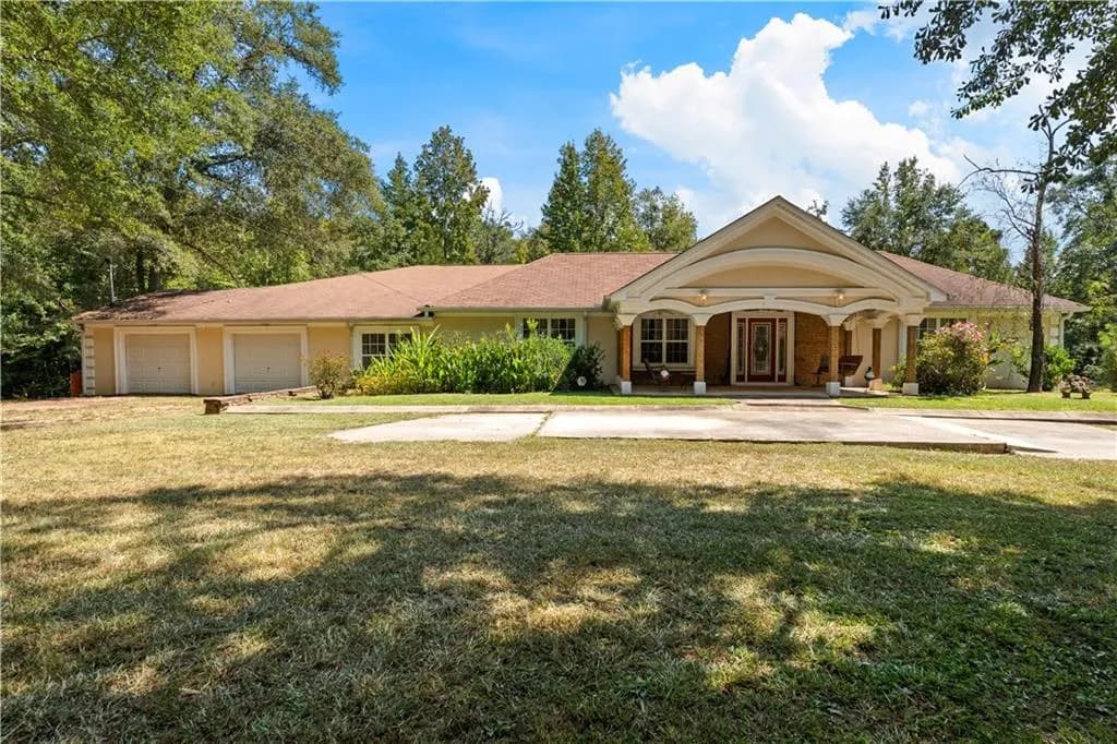 View of front of property featuring a front yard, a porch, concrete driveway, a garage, and stucco siding